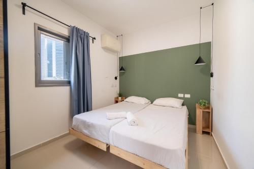 a bedroom with a bed with white sheets and a window at Urban Nest Yaavetz Tlv in Tel Aviv