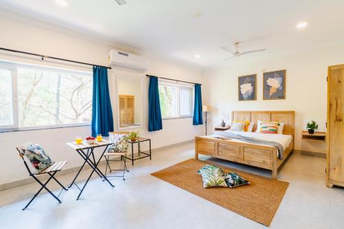 a bedroom with a bed and a table at Mona Collective at Serenova in Calangute