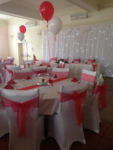 a room with white tables with red bows and balloons at The Bridge Hotel in Scunthorpe
