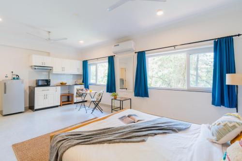 a bedroom with a large bed with blue curtains at Mona Collective at Serenova in Calangute