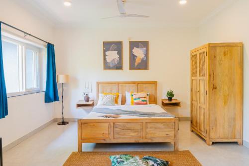 a bedroom with a bed and a wooden cabinet at Mona Collective at Serenova in Calangute