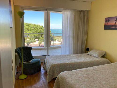 une chambre d'hôtel avec deux lits, une chaise et une fenêtre dans l'établissement APPARTEMENT T3 VUE MER grande terrasse, à Arcachon