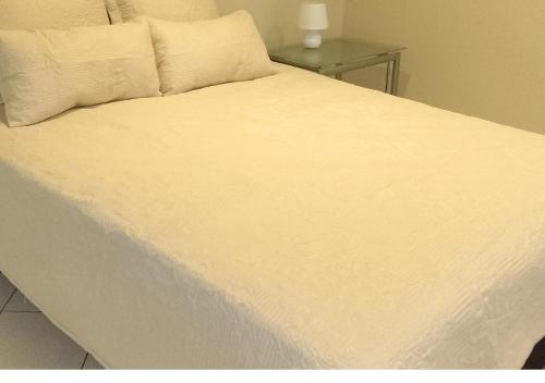 a large white bed with white sheets and pillows at Suider Ozias Self Catering in Windhoek