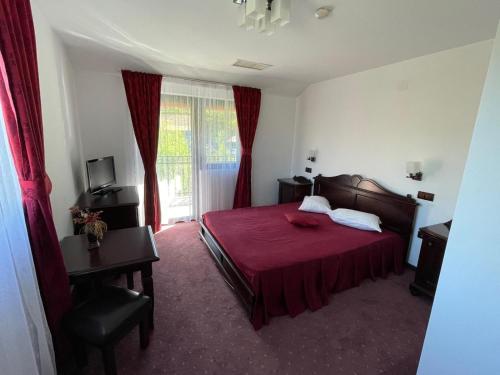 a bedroom with a red bed and a desk and window at Pensiunea Doris in Rodna