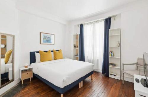 - une chambre avec un grand lit blanc et des oreillers jaunes dans l'établissement Appartement familial face pantheon - Paris 5 4P, à Paris