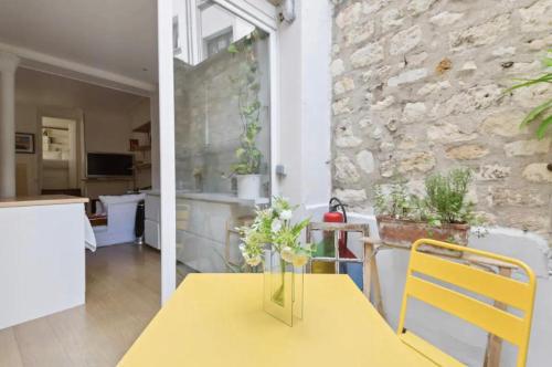 une table jaune avec un vase de fleurs sur elle dans l'établissement Appartement familial face pantheon - Paris 5 4P, à Paris