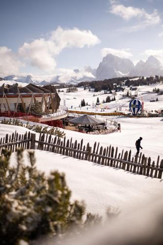 a person skiing down a snow covered slope with a fence at COMO Alpina Dolomites in Alpe di Siusi