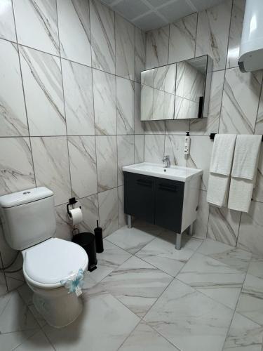 a white bathroom with a toilet and a sink at Inn City Park Hotel in Burunabat