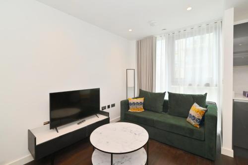 a living room with a green couch and a table at Access Tower Hill in London