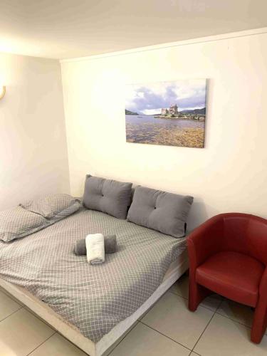 a bed with a red chair and a picture on the wall at Studio SCOTTLAND in Chambéry