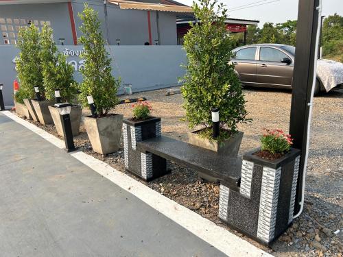 a row of potted trees and a bench in a parking lot at V Rich วีริชเพลส ร้อยเอ็ด in Ban Non Muang