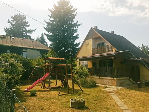 a yard with a playground in front of a house at Kristóf apartman in Gyenesdiás