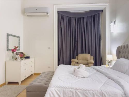Un dormitorio con una cama blanca y una silla. en 2BR Downtown Alia Khan, Fully equipped Gem, en El Cairo