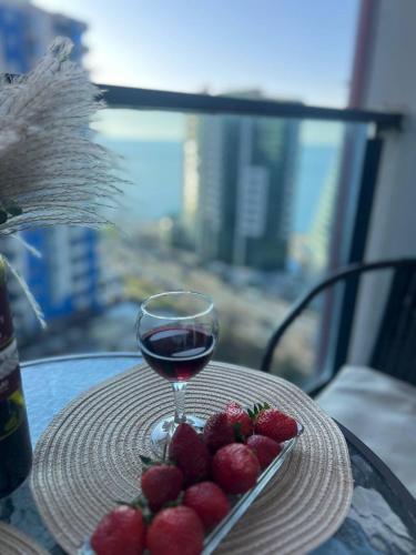 a plate of strawberries and a glass of wine on a table at Boho apartment studio in Batumi