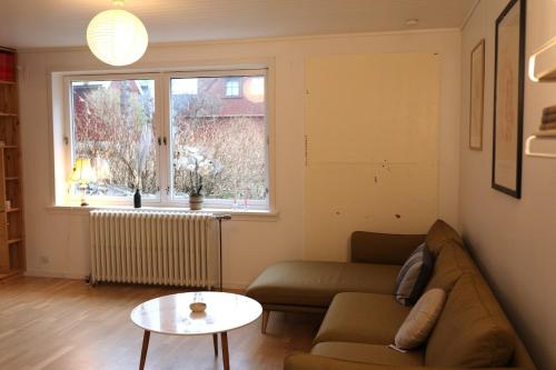 a living room with a couch and a table and a window at Historical and cosy house in the heart of Tórshavn in Tórshavn