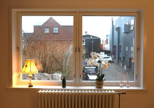 a window with flowers in a vase on a radiator at Historical and cosy house in the heart of Tórshavn in Tórshavn