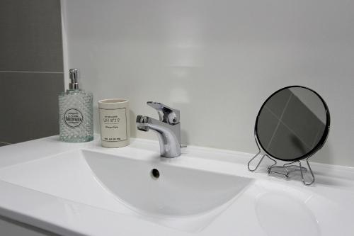 La salle de bains est pourvue d'un lavabo avec miroir et d'un distributeur de savon. dans l'établissement Victoria1 - Nice apartment 4ppl near Disneyland, à Serris