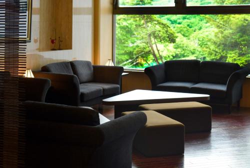 a waiting room with couches and tables and a large window at Hotel Kanronomori in Niseko