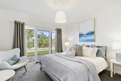 a white bedroom with a bed and a chair at Bimbadeen Luxurious Retreat in Aireys Inlet