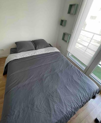 un lit dans une chambre avec une grande fenêtre dans l'établissement Studio tout équipé, fonctionnel avec parking privatif, à La Rochelle