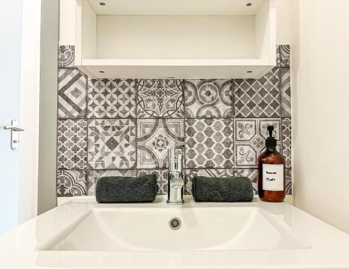 - un lavabo blanc dans la salle de bains avec une bouteille de vin dans l'établissement Studio tout équipé, fonctionnel avec parking privatif, à La Rochelle