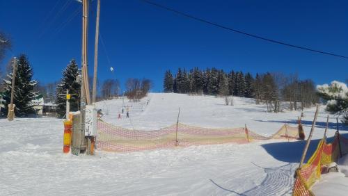 a ski slope with an orange fence in the snow at Penzion V Kopci in Kořenov