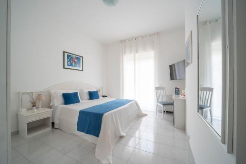 a white bedroom with a bed and a table and chairs at Hotel Panorama in Maiori