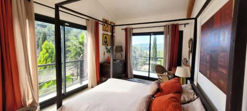 ein Schlafzimmer mit einem Bett und einem großen Fenster in der Unterkunft Les Cyprès de Chaume in Vidauban