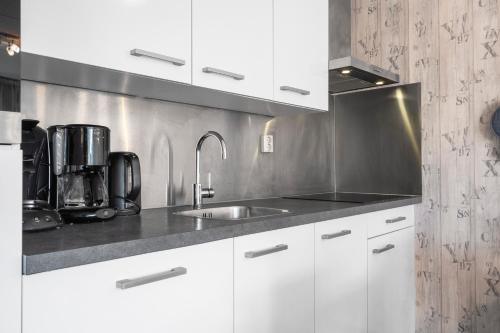 a kitchen with white cabinets and a sink at Beach Appartement 14 - Aan de duinen, Callantsoog aan Zee in Callantsoog