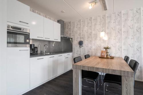 a kitchen with white cabinets and a wooden table at Beach Appartement 14 - Aan de duinen, Callantsoog aan Zee in Callantsoog