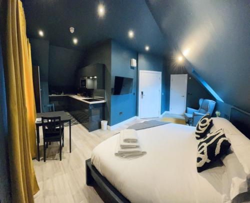 a bedroom with a large white bed and a kitchen at Sky City Apartments in Coventry