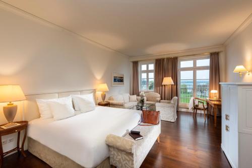 a bedroom with a large white bed and a living room at Sunday Schwielowsee Resort - Hotel in Werder