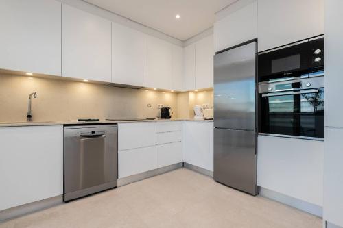 a kitchen with white cabinets and a stainless steel refrigerator at Sunset View Apartment in Conceicao de Tavira in Tavira