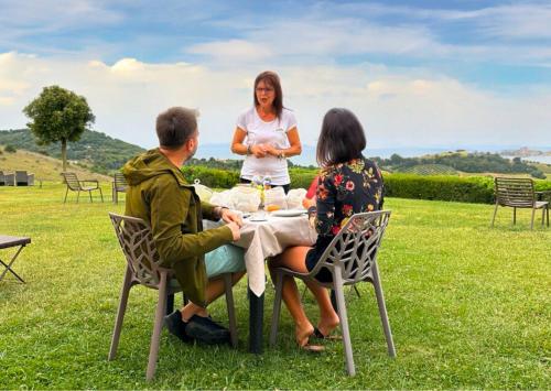 a group of people sitting around a table in the grass at Agriturismo La Vista - Adults Only in Fonteblanda