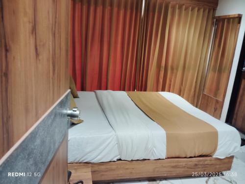 アーメダバードにあるHotel Peragon Innのベッドと赤いカーテンのある寝室
