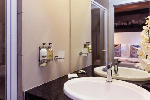 a bathroom with two sinks and a mirror at Akanani Apartments in Pretoria