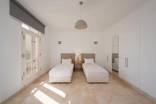 two beds in a room with white walls at VESTA - El Gouna Residence in Hurghada