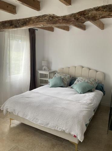 une chambre avec un grand lit blanc avec des oreillers bleus dans l'établissement Cottage normand de 1930, à Manneville-sur-Risle