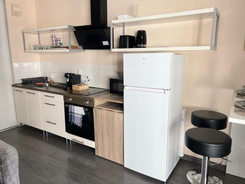 - une cuisine avec un réfrigérateur blanc et deux tabourets dans l'établissement Studio élégant avec balcon près de la plage à Nice, à Nice