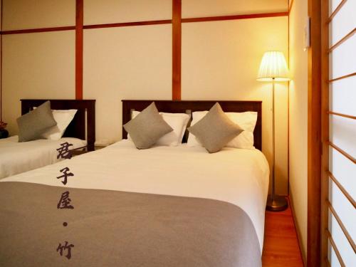 a hotel room with two beds with chinese writing on them at 君子屋竹Hotel l 5 Min to USJ l Near Umeda&Nipponbashi l 2bedroom villa l Direct Airport Access in Osaka