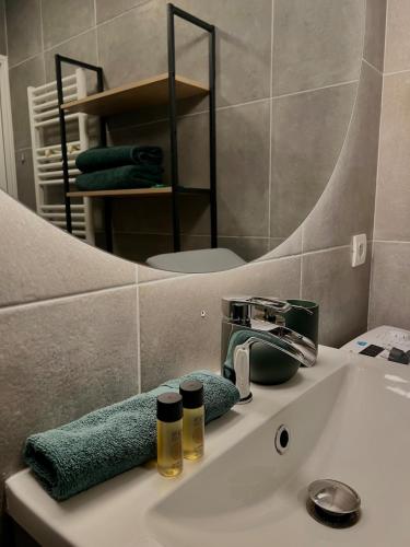 La salle de bains est pourvue d'un lavabo avec miroir et d'une serviette verte. dans l'établissement Studio élégant avec balcon près de la plage à Nice, à Nice