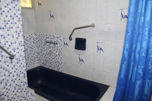 a bathroom with a tub and a blue shower curtain at La casa de Wanda in Oberá