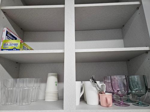 a shelf with glasses and other items on it at Tov Stay Atti in Pyeongtaek