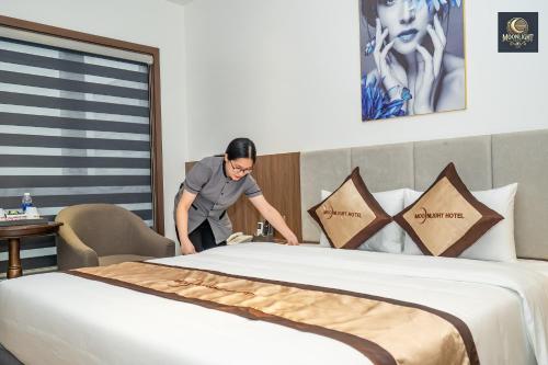 a woman standing next to a bed in a hotel room at Khách sạn MoonLight An Khánh Hà Nội in Vân Lũng