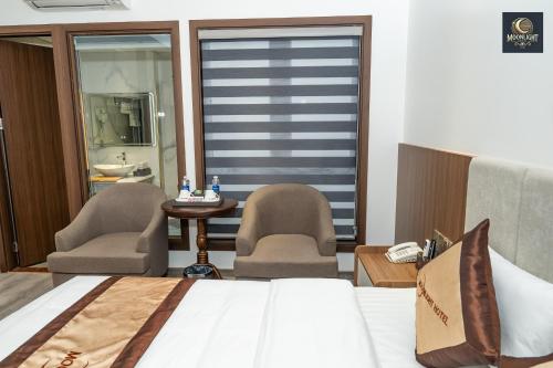 a bedroom with a bed and two chairs and a table at Khách sạn MoonLight An Khánh Hà Nội in Vân Lũng