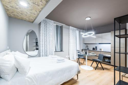a bedroom with a large white bed and a kitchen at Unique design 200 steps from the Aquarium in Genova