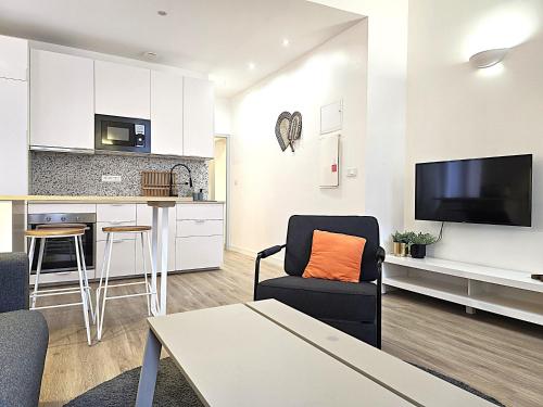 un salon avec un canapé, un fauteuil et une cuisine dans l'établissement Le Sarrail - Appartement 2 à 4 personnes - 1 chambre double séparée - 5 min à pied de la gare et centre ville, à Montauban