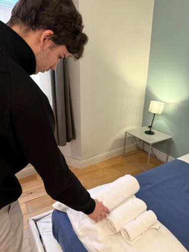 a man is putting towels on a bed at Palazzo Cambiaso Albergo Etico Genova in Genova