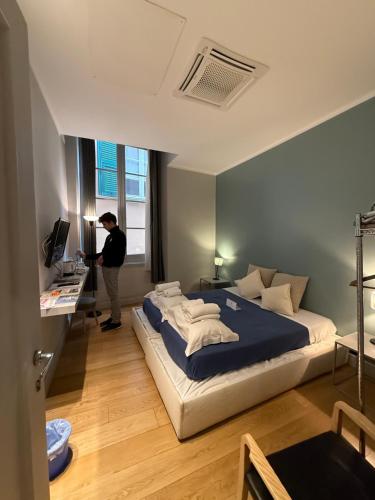 a man standing in a bedroom with a large bed at Palazzo Cambiaso Albergo Etico Genova in Genova
