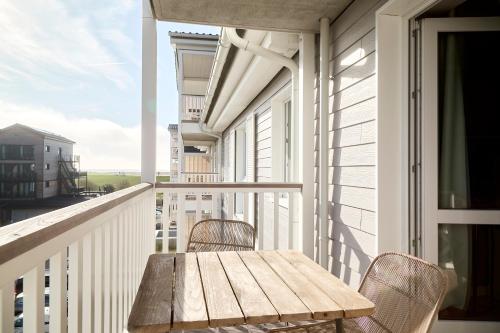 a wooden table on a balcony with a table at Beach Apartments Büsum in Büsum